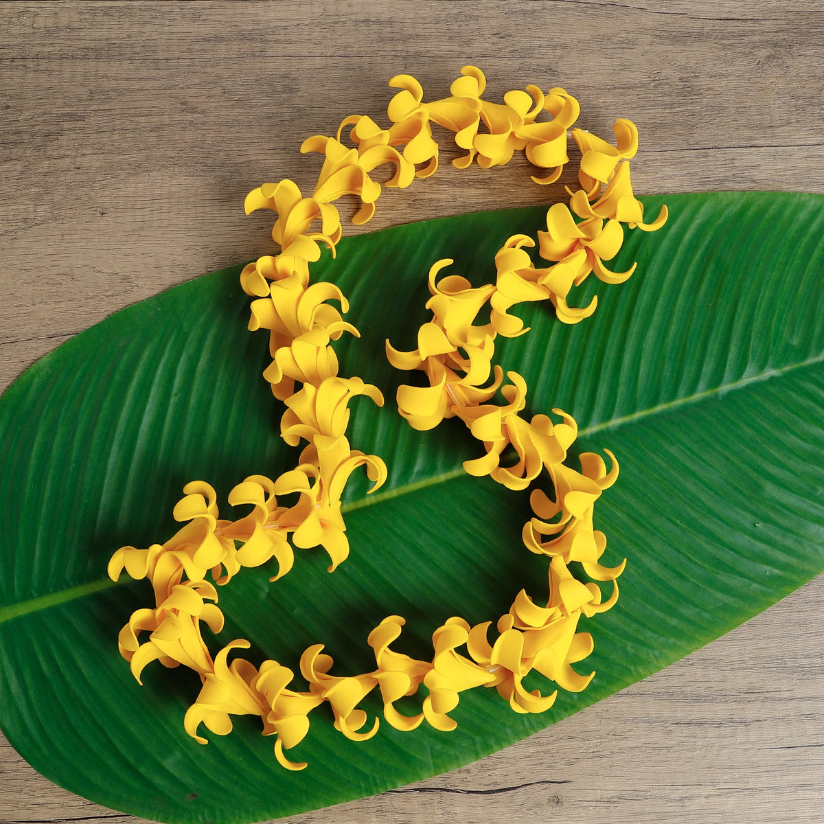 Yellow soft foam Puakenikeni lei arranged as a product scene